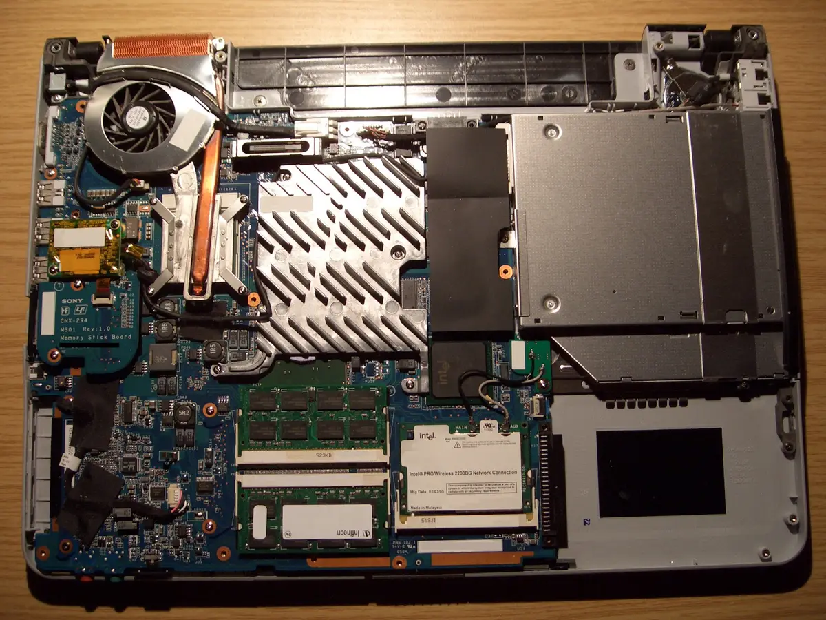Laptop opened up for repair showing the motherboard, cooling fan and memory